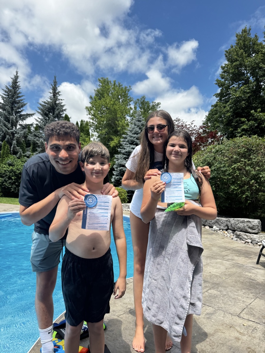 Two swimmers proudly holding their completed progress cards